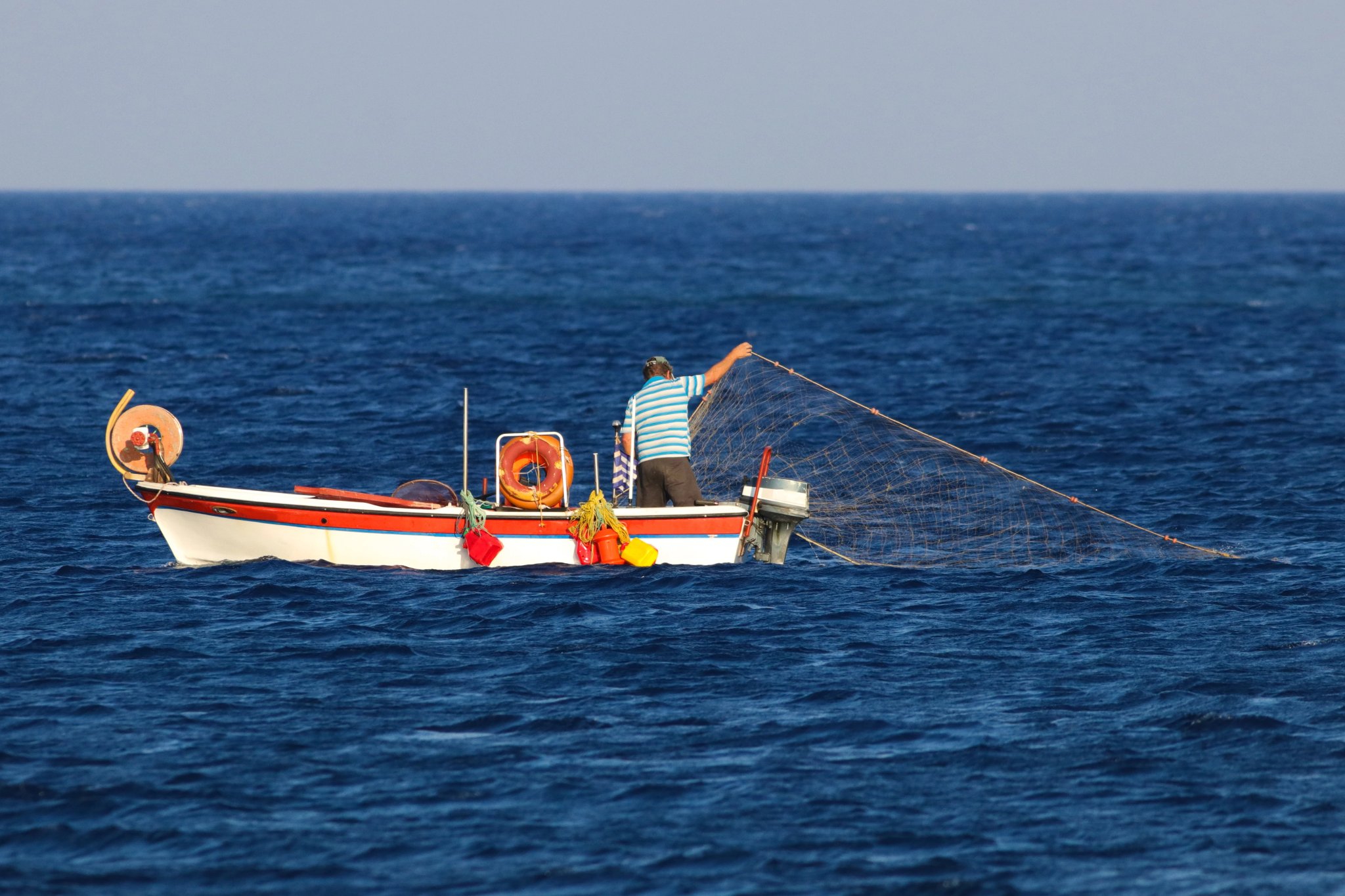 Greek fishermen using fishing nets on the boat