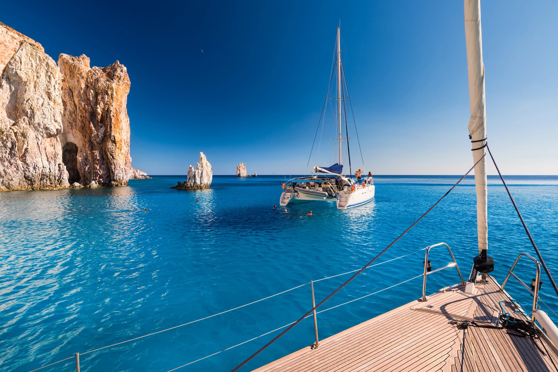 Boats at anchor in the turquoise sea of the south coast of the uninhabited island of Poliegos near Milos in the Greek Cyclades