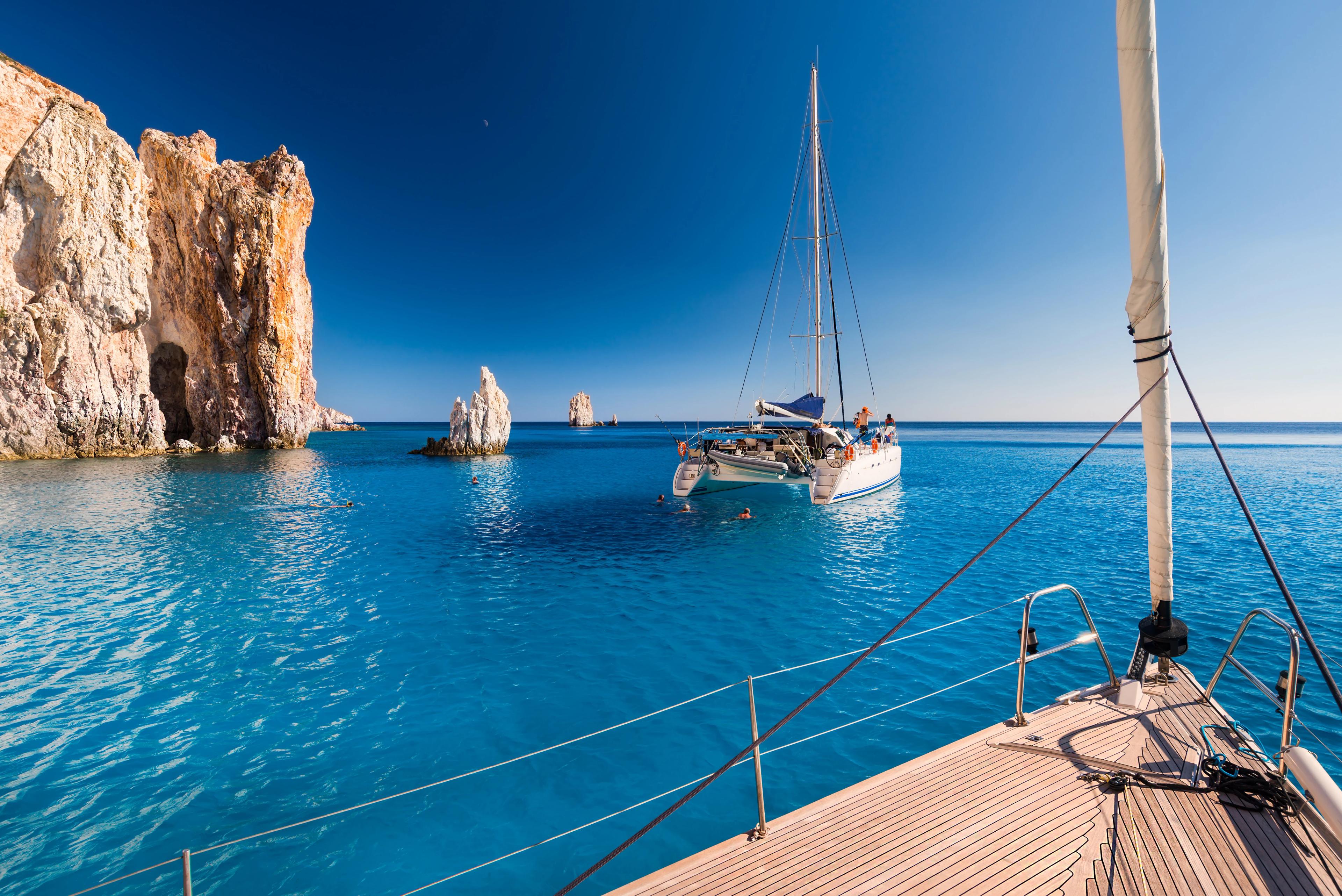 Boats at anchor in the turquoise sea of the south coast of the uninhabited island of Poliegos near Milos in the Greek Cyclades