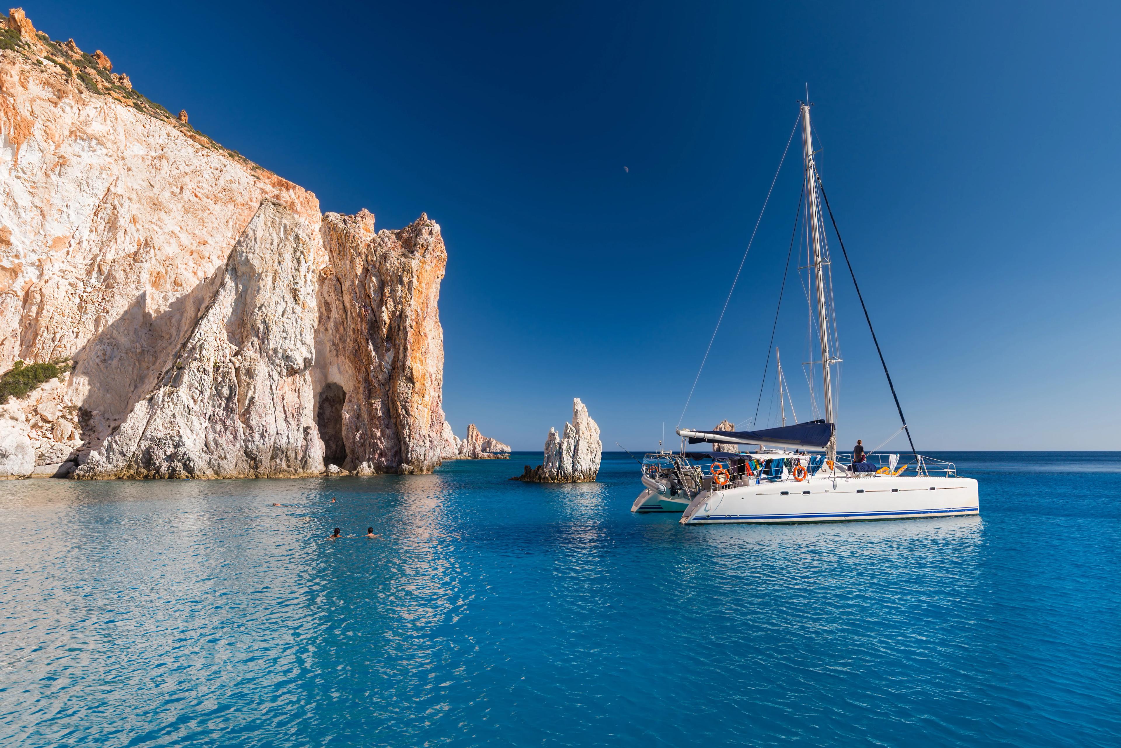 Boats at anchor in the turquoise sea of the south coast of the uninhabited island of Poliegos near Milos in the Greek Cyclades