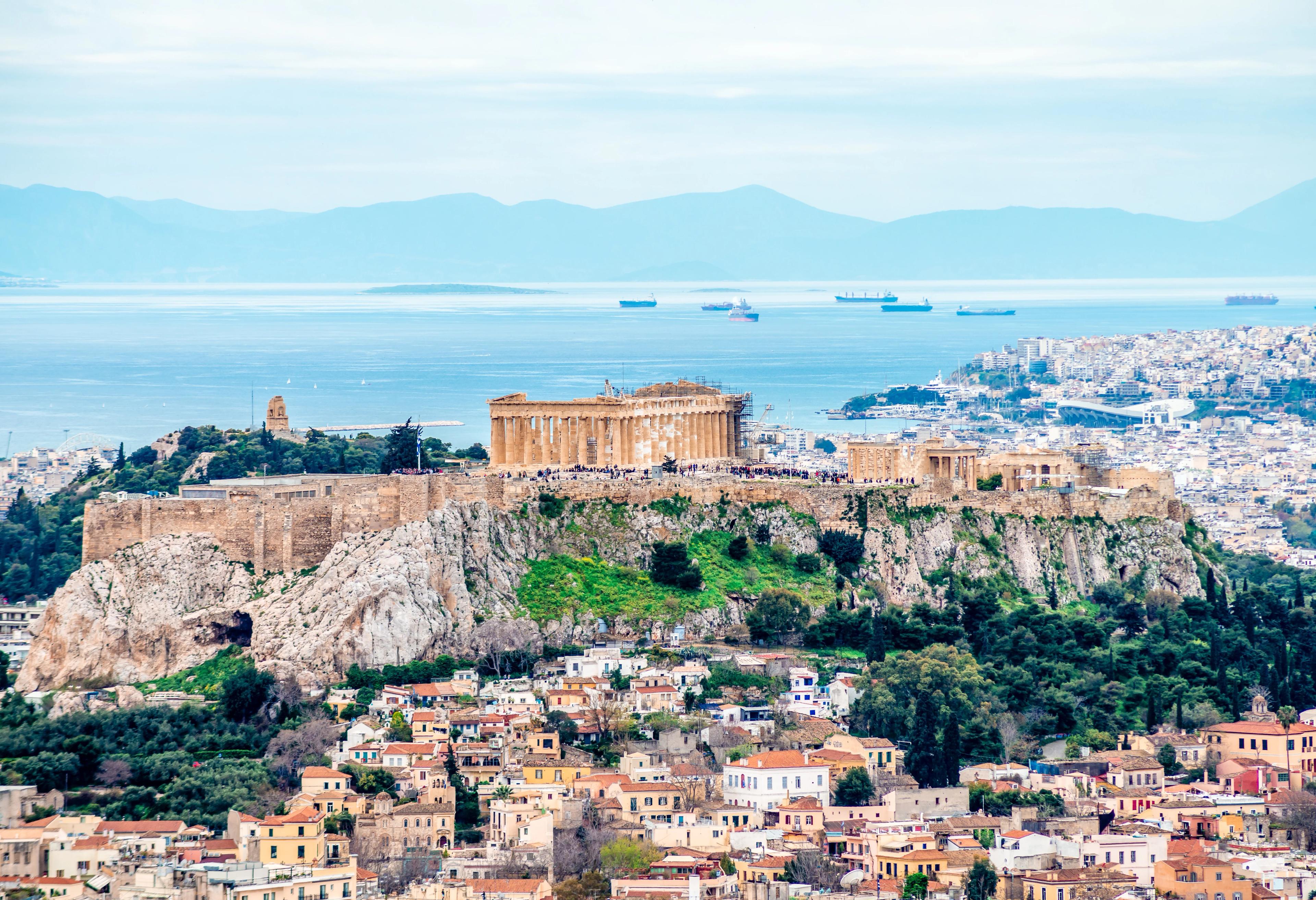 View of the Acropolis of Athens (in Greece) with Filopappos Hill, the Saronic gulf and the port of Piraeus in the background.