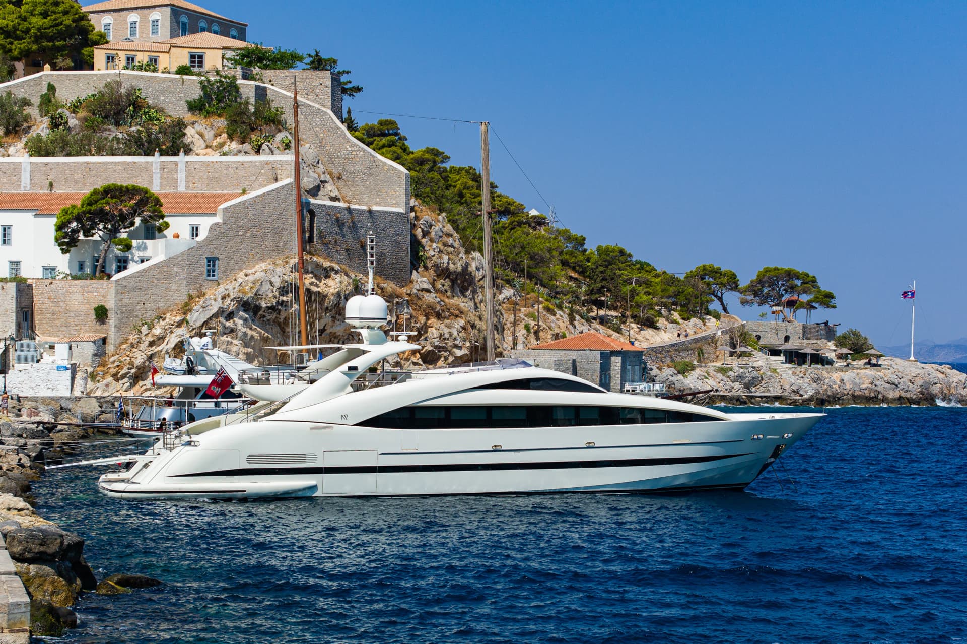 Luxurious Yacht at port of Hydra island with traditional houses on the background