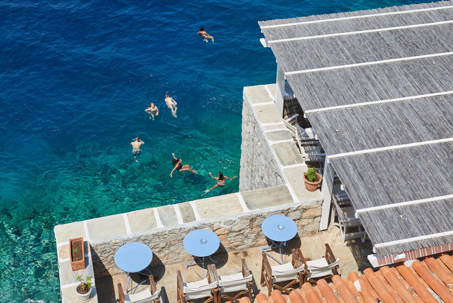 People enjoy the turquoise sea at hydra island , Greece