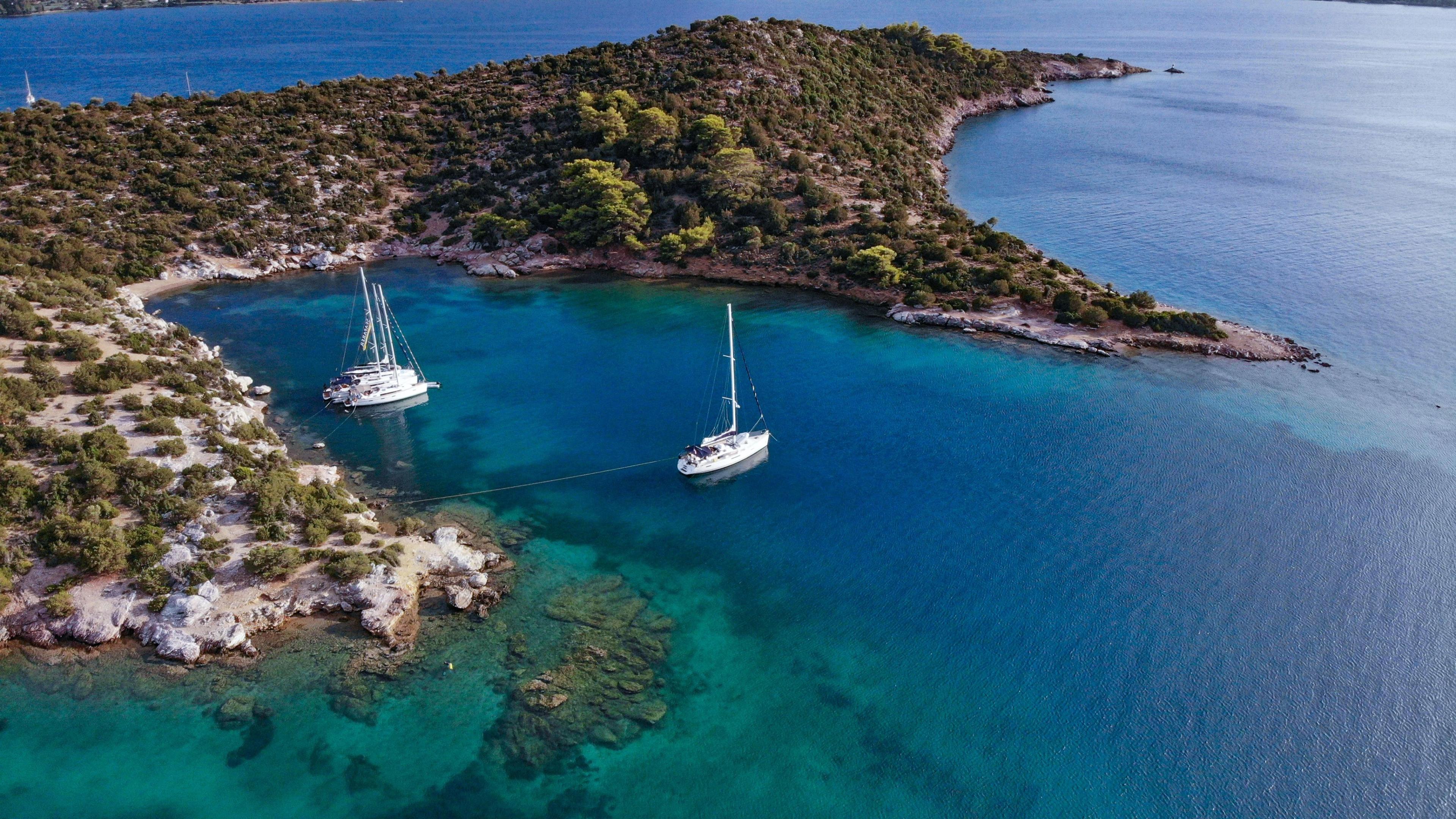 Yachts are moored in a tranquil, picturesque setting on Poros island in the middle of the sea