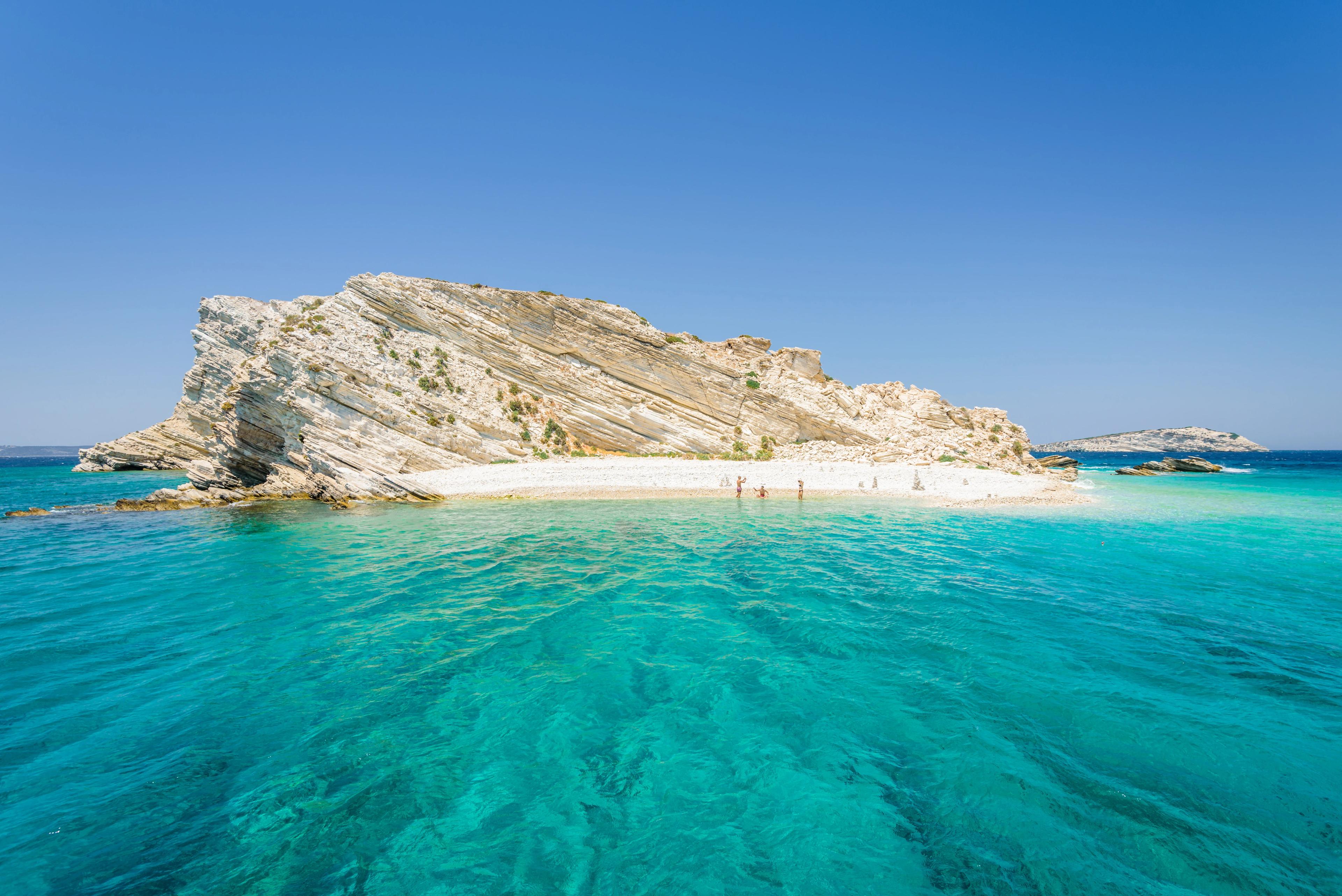 Beautiful sunny coast view to a small greek island and crystal clear blue water beach with some boats cruising and people swimming, White Island, Aspronisi, Leros, Dodecanese/ Greece – July 22 2017
