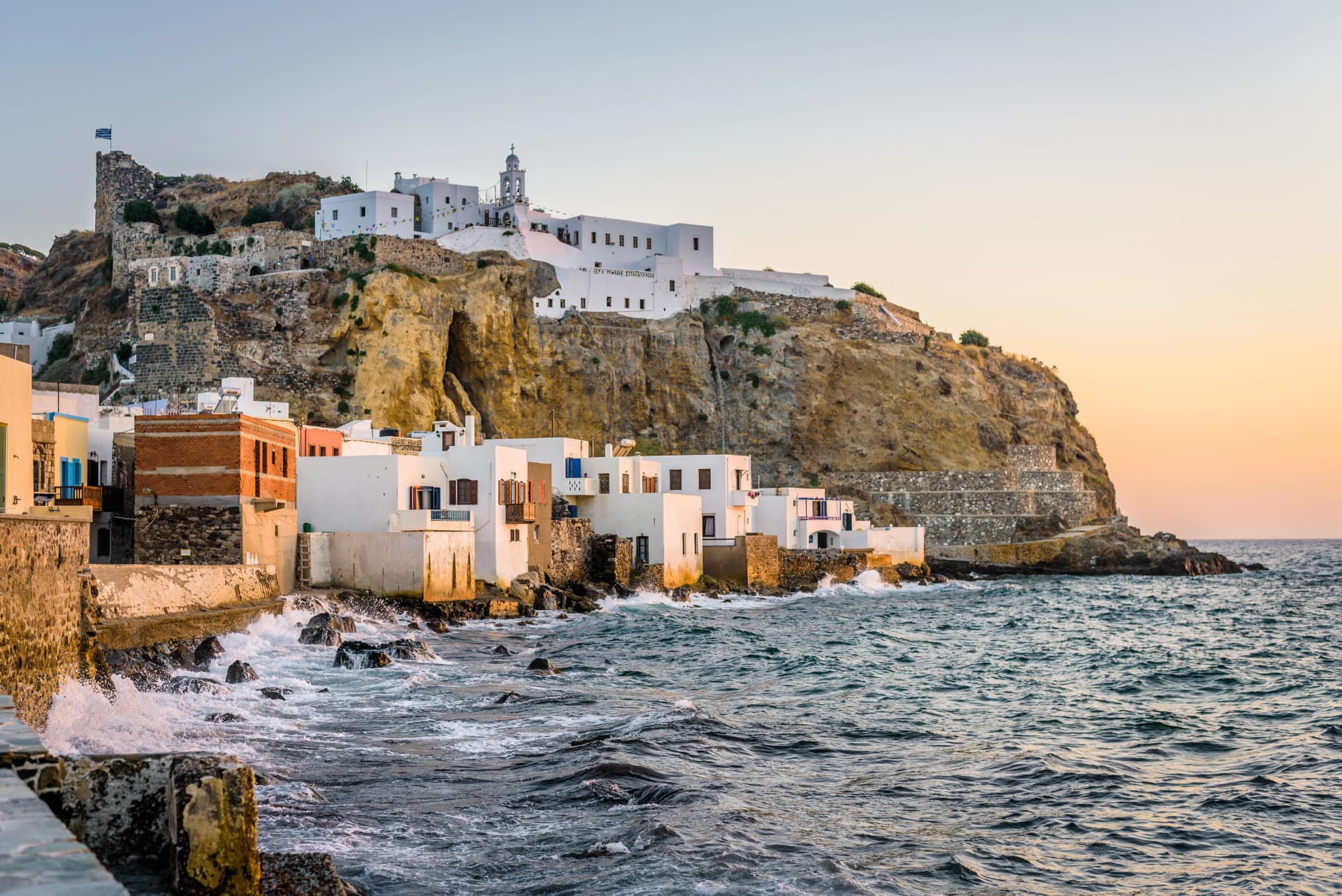 Beautiful sunset sunrise coast view to old ancient monastery church on a cliff of mediterranean greek village Mandraki, Monastery of Panagia Spiliani, Nisyros Island, Kos, Dodecanese, Greece