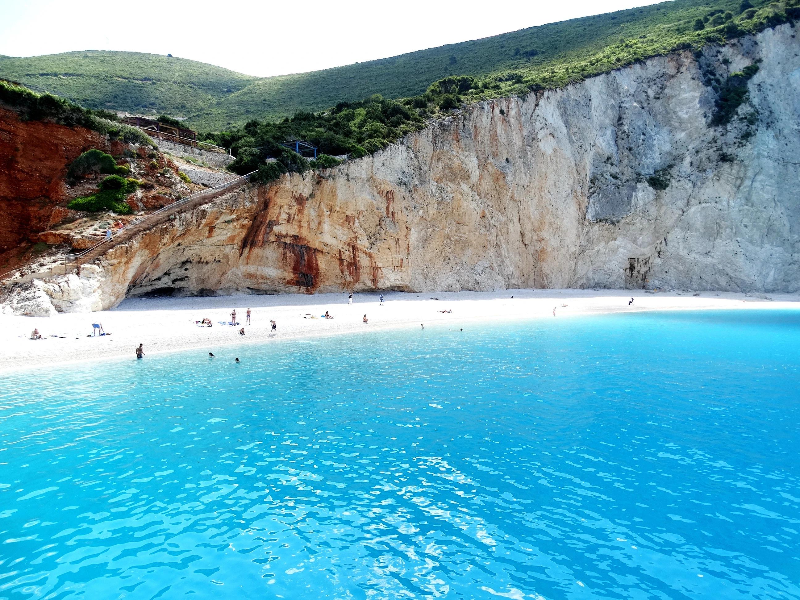 Porto Katsiki beach natural landscape and seascape with island, cliff, rock, plant, sea cave, blue sky, and sunray. Travel destination in western Greece of Ionian Islands, Lefkas, Kefalonia, Meganisi