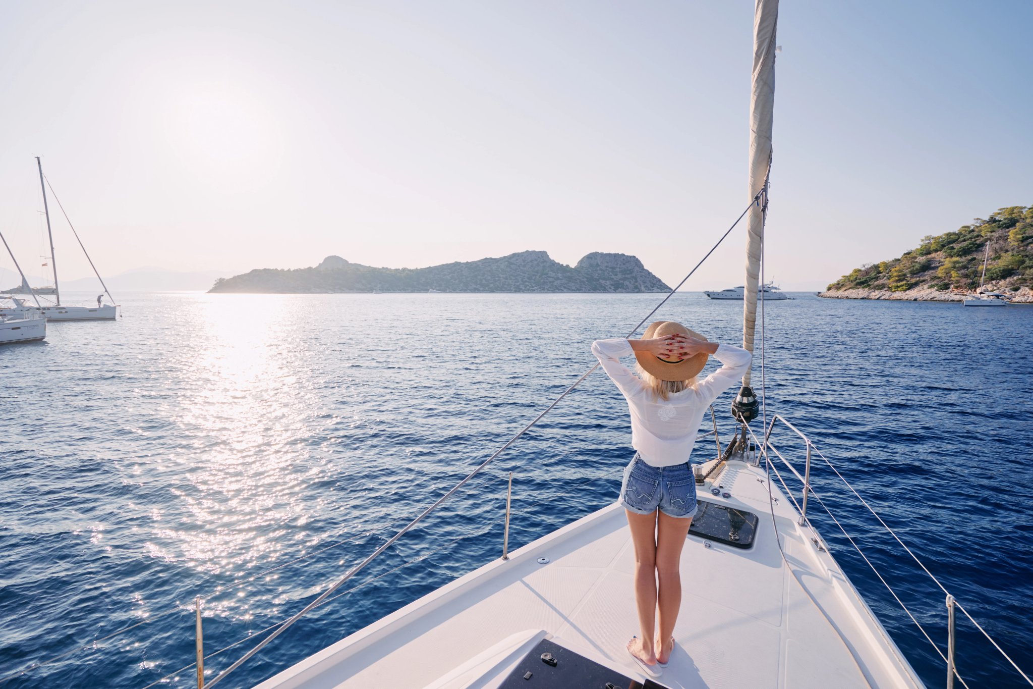 Luxury travel on the yacht. Young happy woman on boat deck sailing the sea. Yachting in Greece.