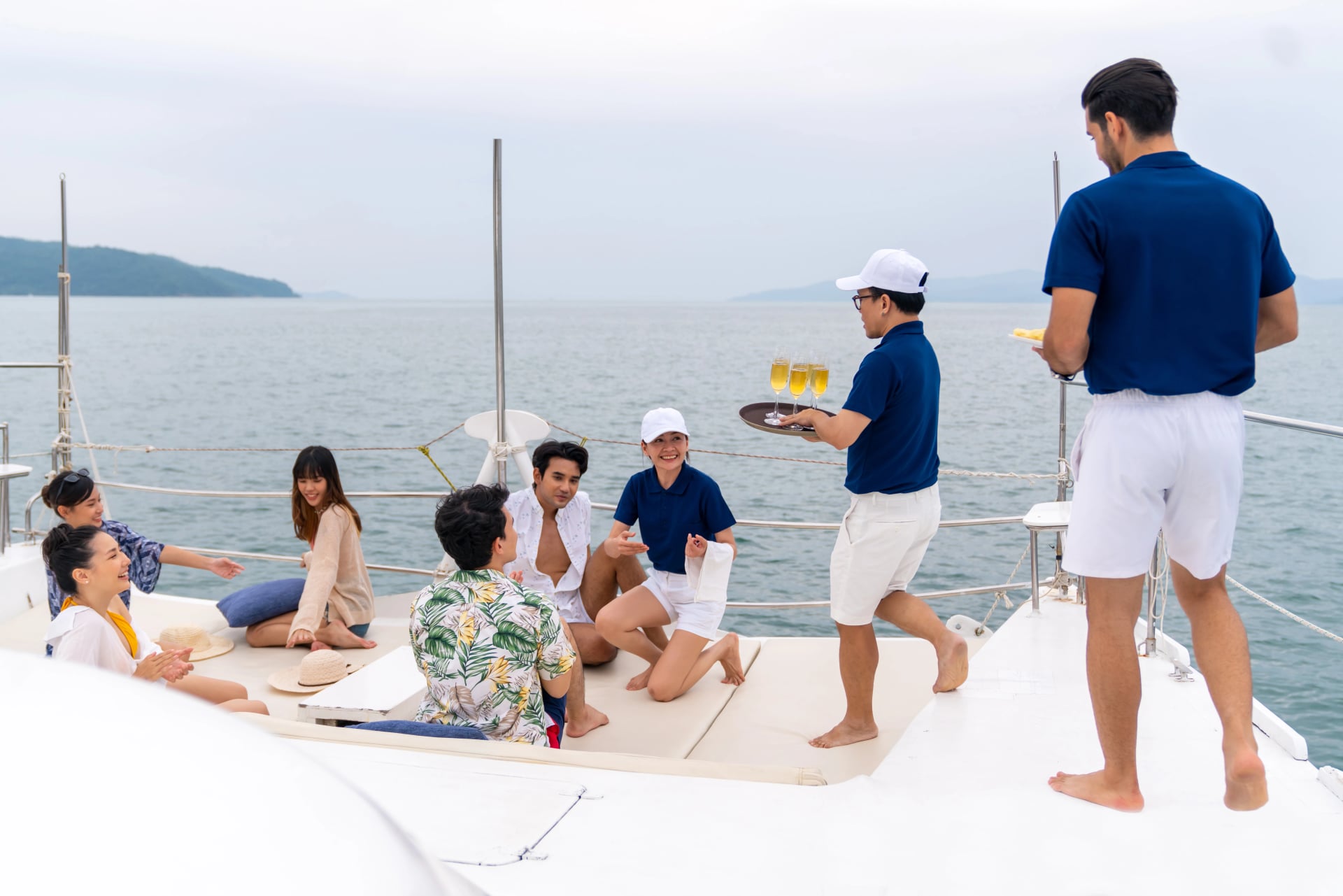 L'équipage du yacht servant des fruits et du champagne à un touriste passager lors d'une fête de célébration sur un yacht catamaran de luxe naviguant dans l'océan pendant des vacances d'été. Service de croisière.